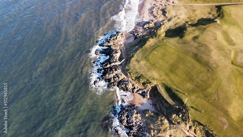 Aerial view looking out over North Berwick town and golf course with waves crashing onto the shore. North Berwick Scotland. 