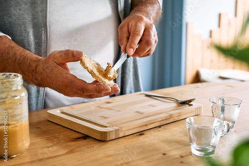 Man making healthy breakfast or brunch, spreading peanut butter on a puffed corn cakes. Protein diet healthy eating concept. photo