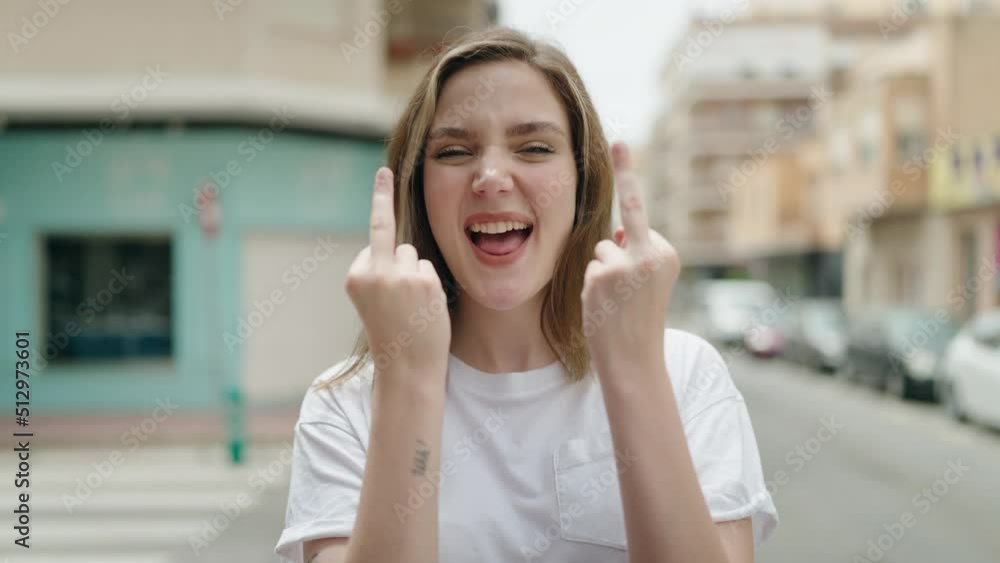 Young woman smiling confident doing bad gesture with fingers at street Young woman smiling confident doing bad gesture with fingers at street