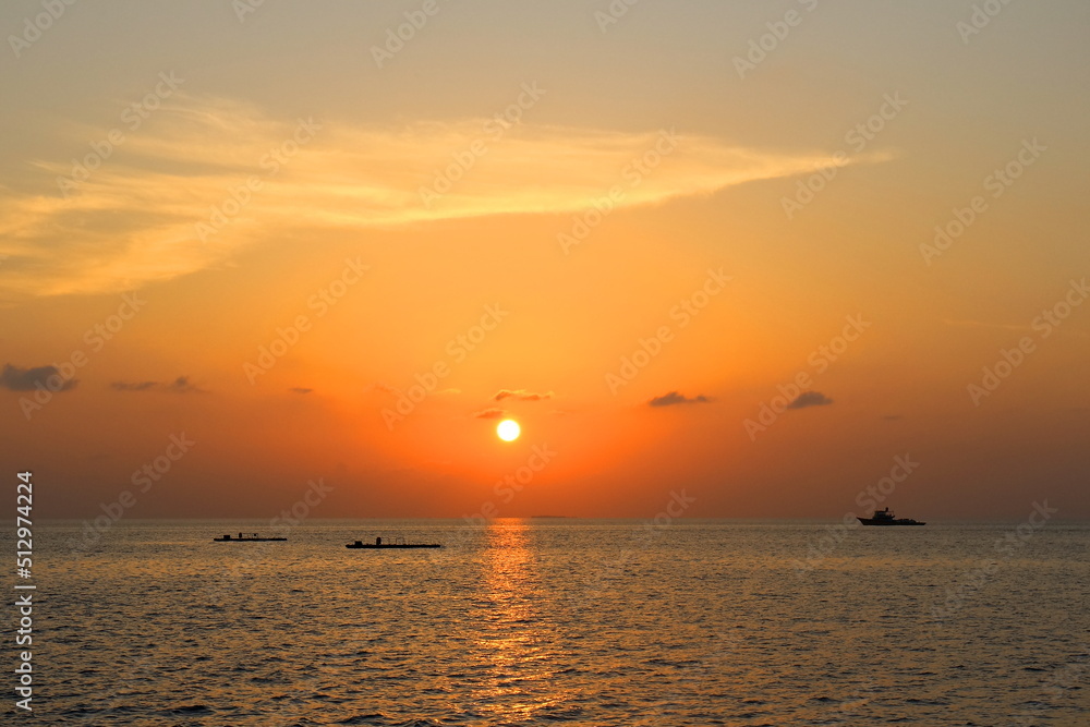 Sunset on Maldives island with boat and reflection of sunlight on sea, view from travel boat. Low key. Nature and travel in summer concept.