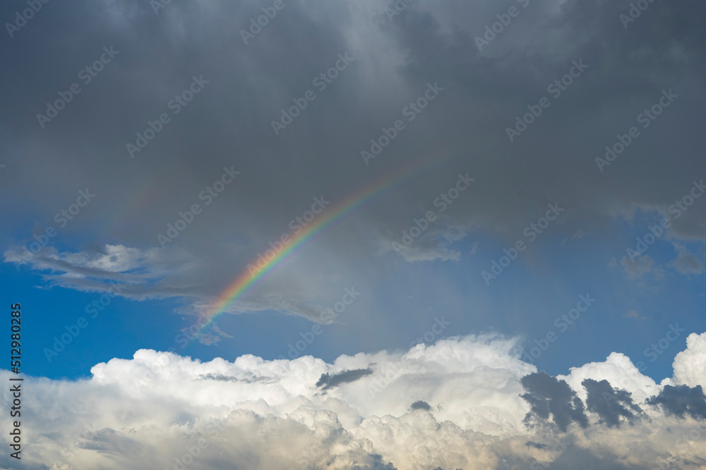 A rainbow arc across the sky during a rainstorm A rainbow arc across the sky during a rainstorm