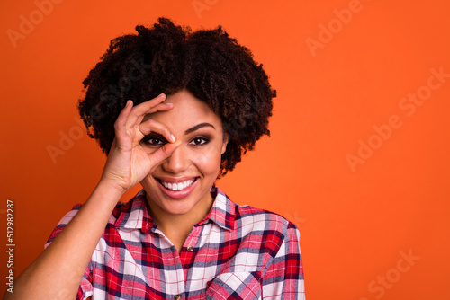 Photo of carefree cheerful person arm make binocular eye look camera isolated on orange color background © deagreez