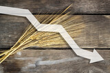 threat of world hunger and food crisis, problems with the supply of food, spikelets of wheat on a wooden background with an arrow indicating a decrease