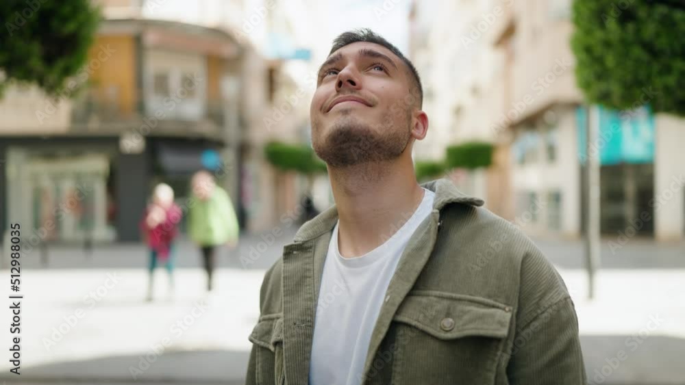 Young hispanic man smiling confident looking to the sky at street