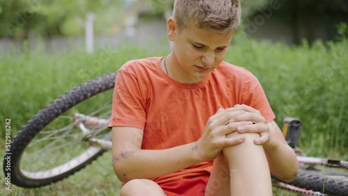 Wound on the knee. Pain from the received blow. The boy cries because of the fall. Accident with a bicycle. An accident in the park. The child cries because his leg hurts. Pity for an injured child.