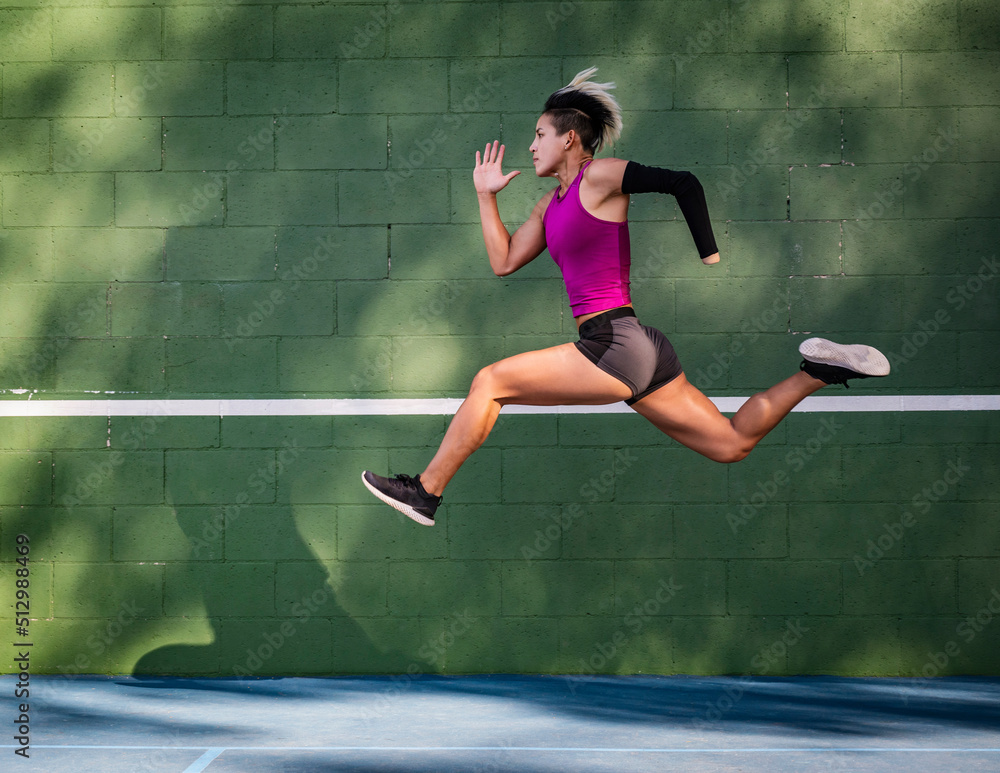 © Tetra Images - Athletic woman with prosthetic arm running against wall