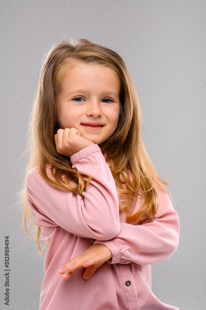 Cute blonde girl in a pink sweater and jeans on a white cube in the studio. Portrait. beautiful girl Cute blonde girl in a pink sweater and jeans on a white cube in the studio. Portrait. beautiful girl