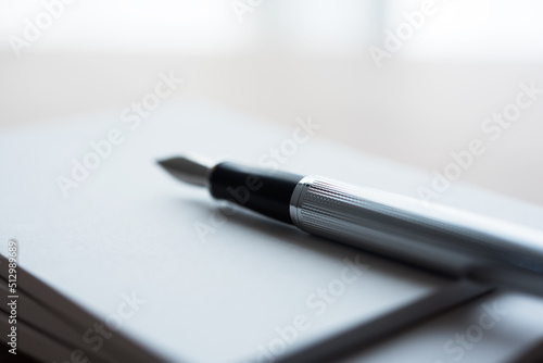 Stylish Silver pen, placed on a blank piece of paper, memo or notepad. Extremely shallow depth of field.