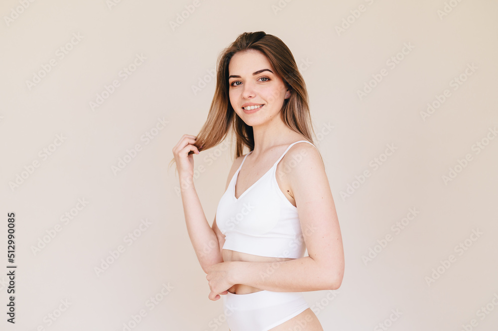 Woman in White Top and Shorts with Beautiful Body Poses on Beige Background. Concept Hair care. Woman in White Top and Shorts with Beautiful Body Poses on Beige Background. Concept Hair care.