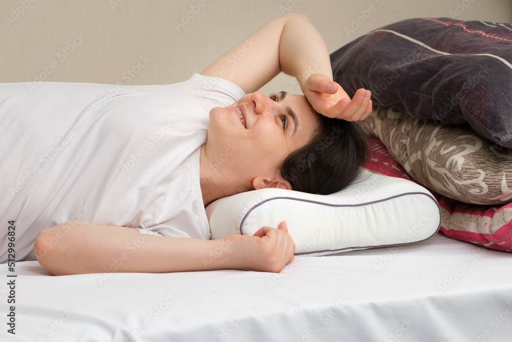 A woman sleeps on an orthopedic pillow made of memory foam, choosing it instead of other pillows made of fluff and sintepon A woman sleeps on an orthopedic pillow made of memory foam, choosing it instead of other pillows made of fluff and sintepon