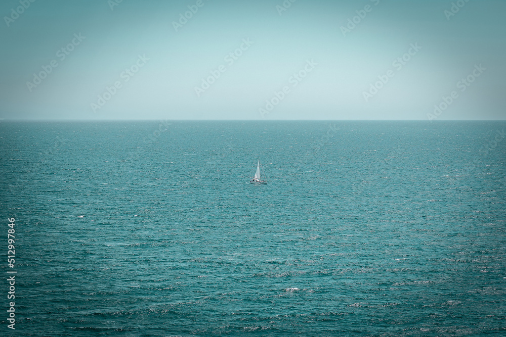 Sailing boat in a distance on open water. Mediterranean Sea with a blue sky