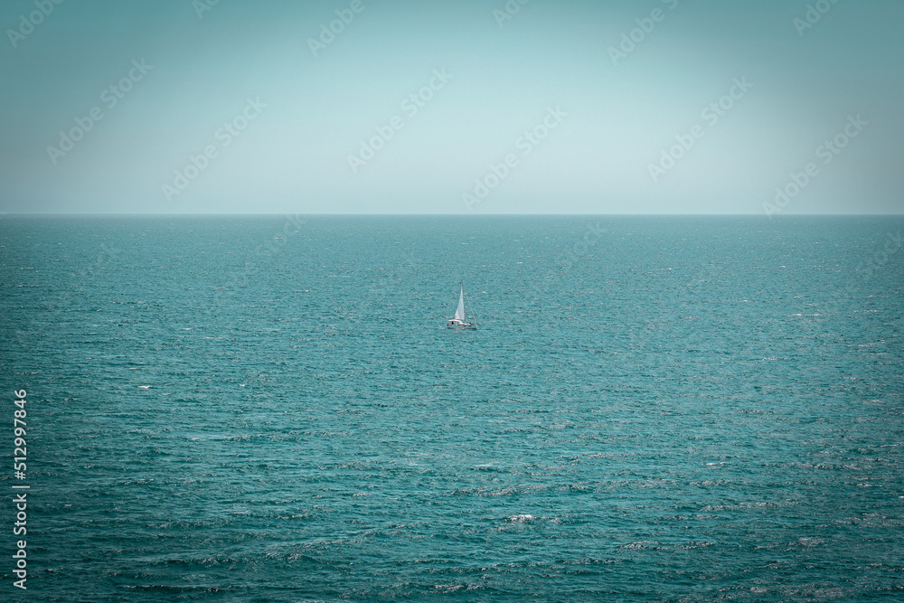 Sailing boat in a distance on open water. Mediterranean Sea with a blue sky Sailing boat in a distance on open water. Mediterranean Sea with a blue sky