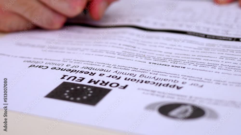 hand of young man fills out the form to apply for a residence permit hand of young man fills out the form to apply for a residence permit