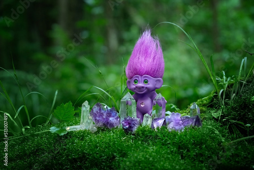tale troll with crystals in forest, natural green background. troll toy with ruffled violet hair in mystery forest, symbol of fairytale. 