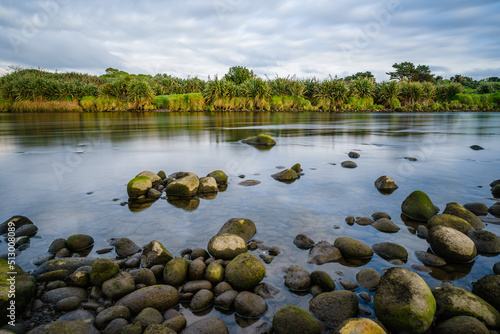 Natural view of the river filled with big rocks in New Plymouth, New Zealand photo