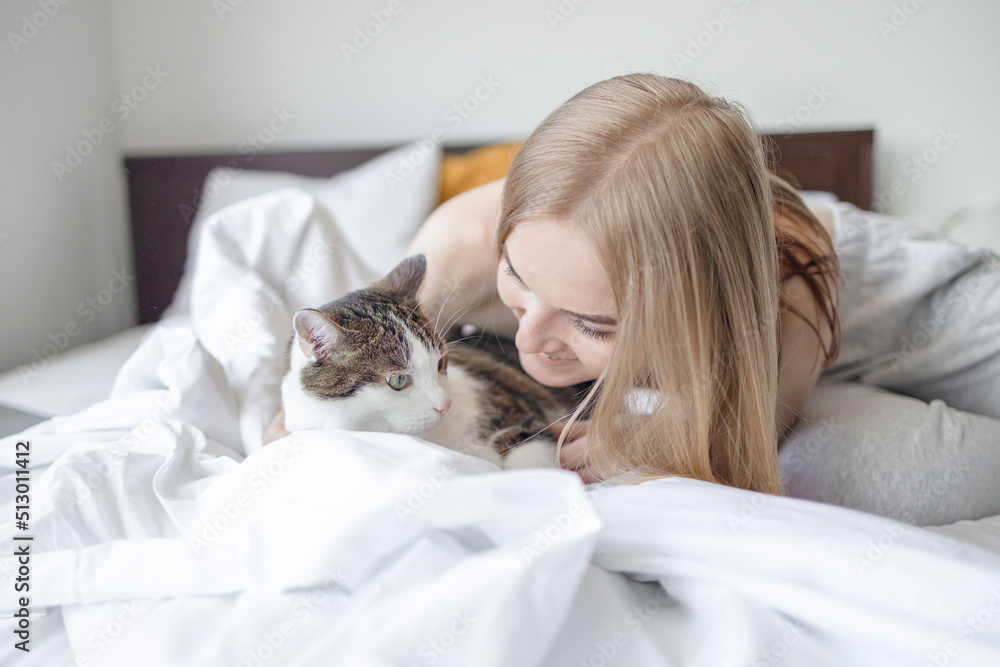 Female hugging cat in hands on the bed at home. Stay home stay safe. Love, care, adoption Female hugging cat in hands on the bed at home. Stay home stay safe. Love, care, adoption
