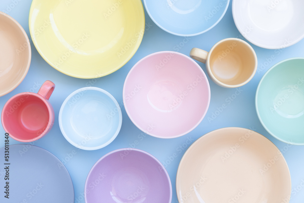 Set of colorful ceramic bowls, plates and cups on blue background. Top view. Set of colorful ceramic bowls, plates and cups on blue background. Top view.