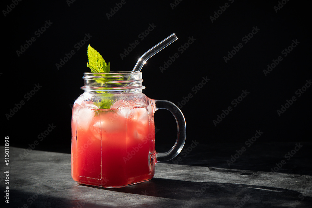 Close-up of fresh watermelon smoothie with ice and mint in jar with straw on black background. Dark low key photo. Selective focus. Blurred background. Close-up of fresh watermelon smoothie with ice and mint in jar with straw on black background. Dark low key photo. Selective focus. Blurred background.