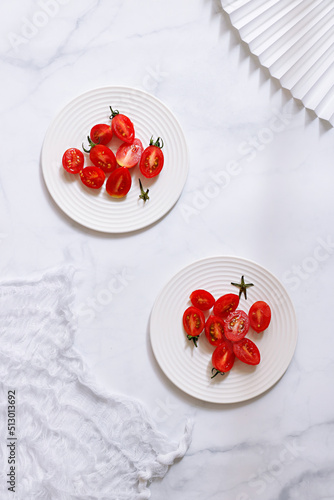 Plates with the sliced cherry tomatoes on the white surface photo