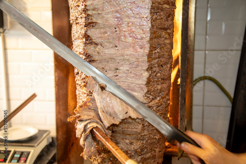 Doner meat being sliced from rotating spit