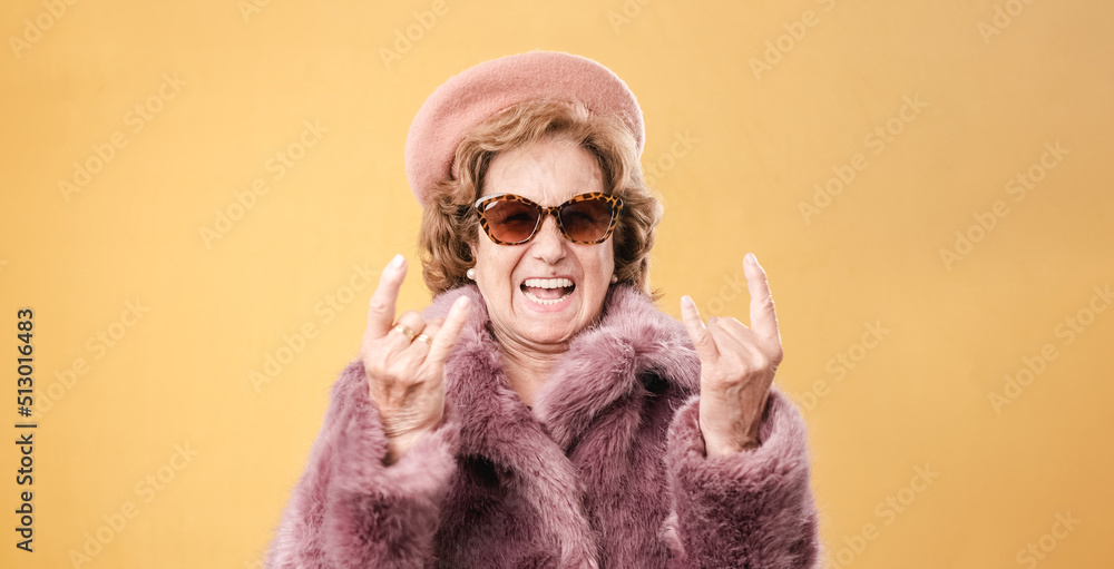 Stylish elderly woman showing rock and roll gesture