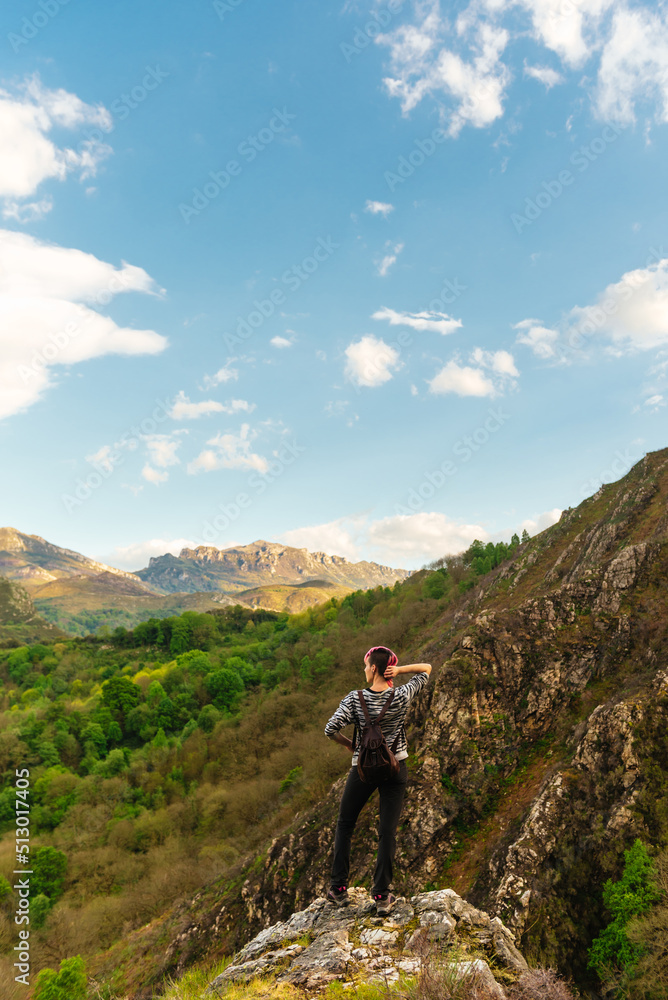 young woman hiker on a rock contemplating the forest while hiking in the mountains.