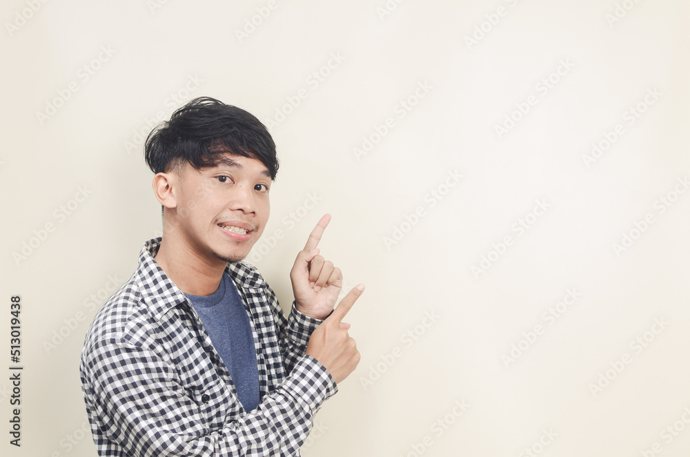Excited Asian man pointing finger at empty space Excited Asian man pointing finger at empty space