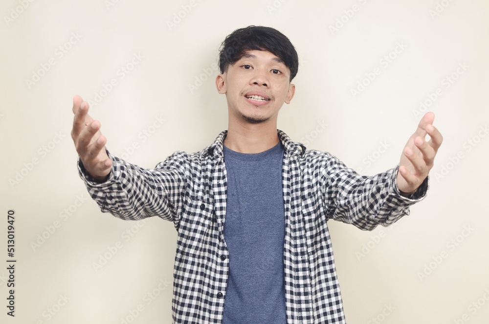 Close-up portrait of happy young Asian male model wearing plaid shirt stretching arms to hug you Close-up portrait of happy young Asian male model wearing plaid shirt stretching arms to hug you