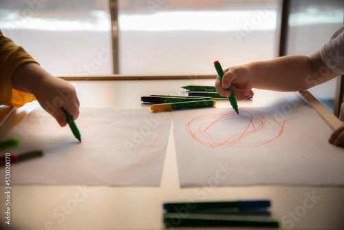 Two kids drawing on white paper