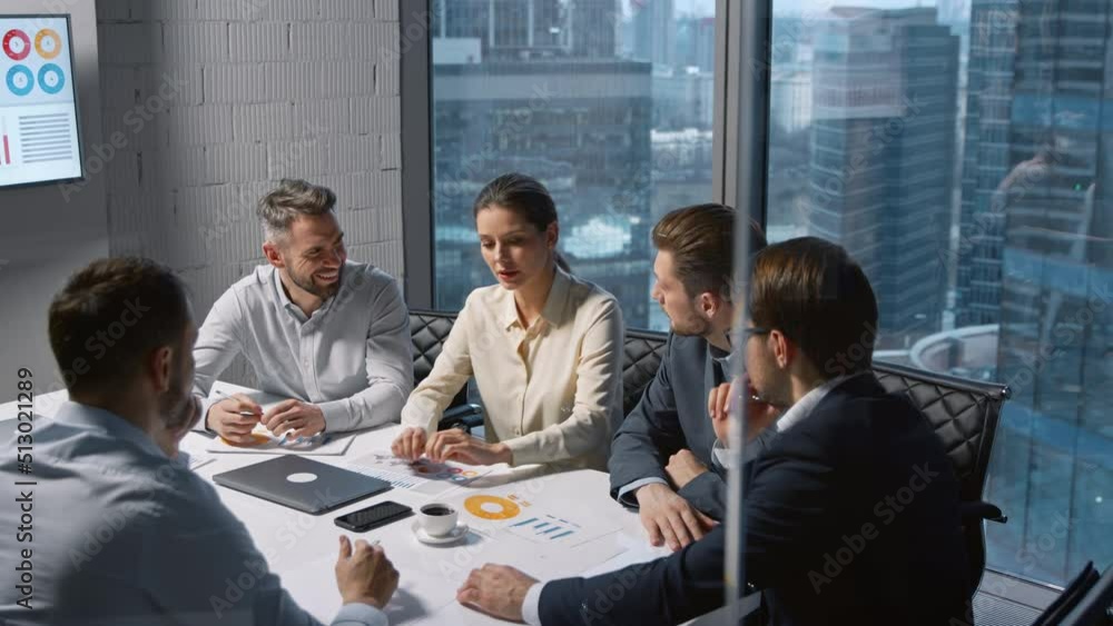 Corporate businesswoman communicating with team while sitting at desk in meeting room Corporate businesswoman communicating with team while sitting at desk in meeting room