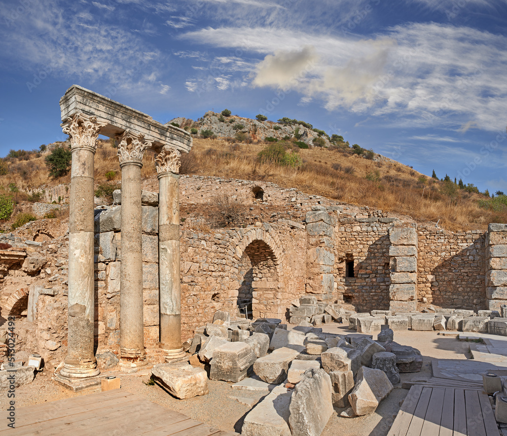 Obraz premium Ancient city ruins and pillars of Ephesus in Turkey in the day. Traveling abroad, overseas for holiday, vacation, tourism. Excavated remains of historical stone building in Turkish history, culture