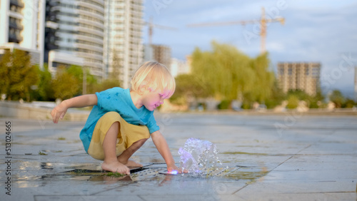 The boy splashes water in the fountain. The baby is wet, but happy. Slow motion