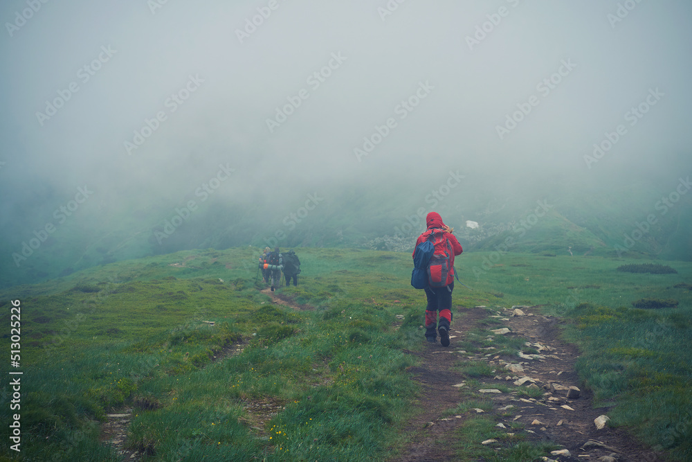 A group of tourists are walking along a mountainous, foggy path. Bad weather in the Carpathian mountains A group of tourists are walking along a mountainous, foggy path. Bad weather in the Carpathian mountains