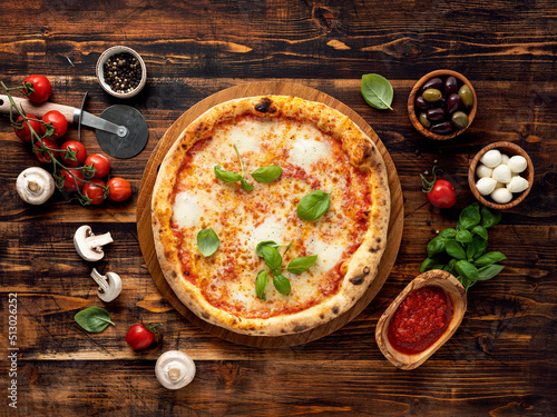 Pizza Margherita and ingredients on wooden background