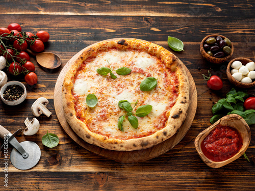Pizza Margherita and ingredients on wooden background