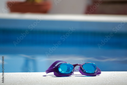 Blue goggles for diving in a pool on a sunny day. © Jose