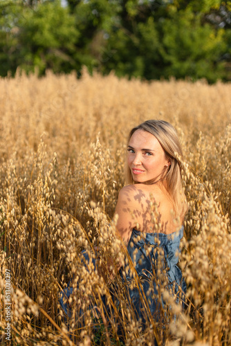 Ukrainian beautiful woman in a blue dress in a yellow wheat field