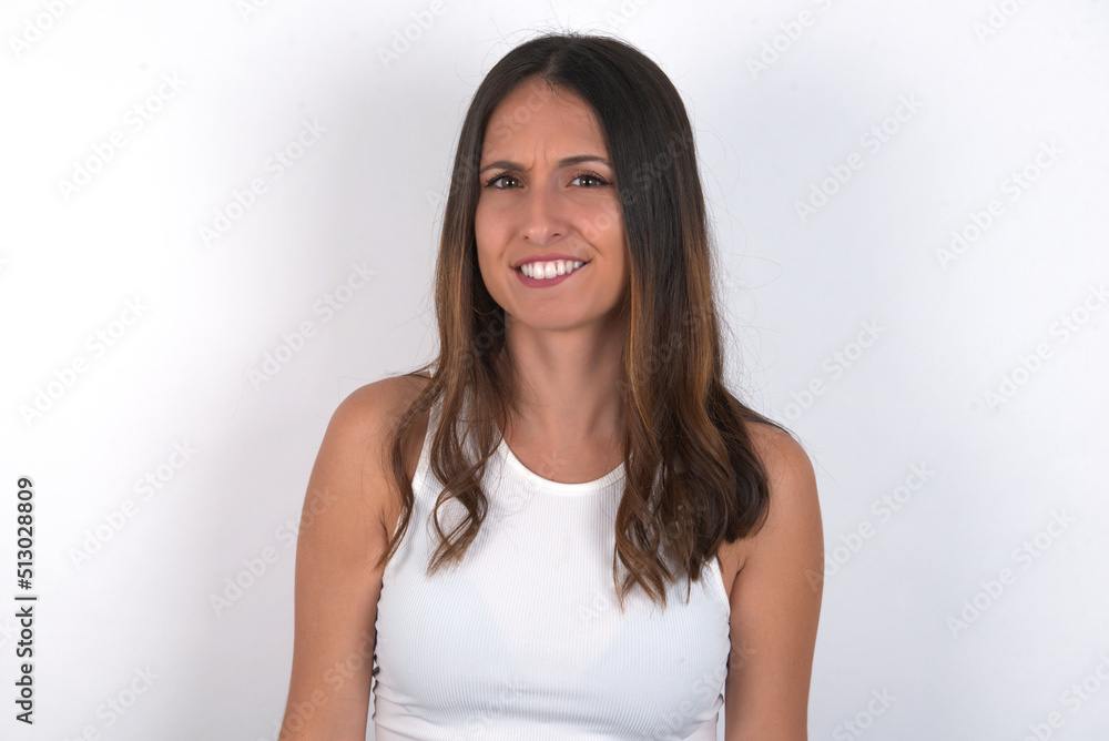 young beautiful caucasian woman wearing white top over white background being nervous and scared biting lips looking camera with impatient expression, pensive. young beautiful caucasian woman wearing white top over white background being nervous and scared biting lips looking camera with impatient expression, pensive.