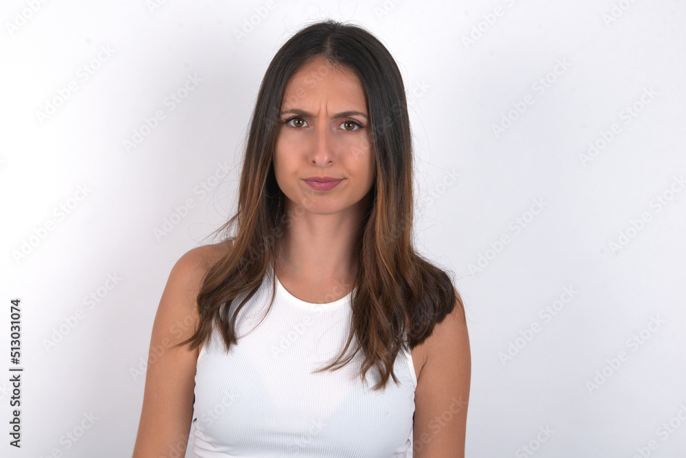 young beautiful caucasian woman wearing white Top over white background, Pointing down with fingers showing advertisement, surprised face and open mouth young beautiful caucasian woman wearing white Top over white background, Pointing down with fingers showing advertisement, surprised face and open mouth