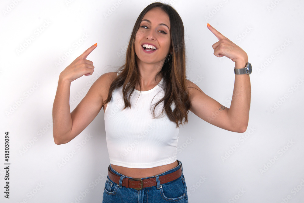 Cheerful young beautiful caucasian woman wearing white Top over white background, demonstrating hairdo Cheerful young beautiful caucasian woman wearing white Top over white background, demonstrating hairdo
