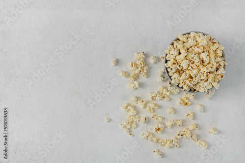 A bowl of delicious popcorn on a light background, top view, copy space