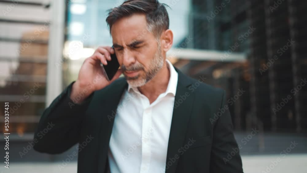 Middle-aged businessman with neat beard in office clothes uses mobile phone. Successful man emotionally talking on smartphone