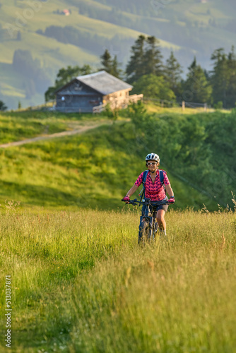 pretty senior woman riding her electric mountain bike on the mountains above Oberstaufen with Nagelfluh mountain chain in background, Allgau Alps, Bavaria Germany © Uwe