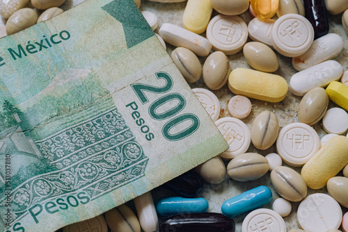 Photo of a Mexican 200 peso bill among pills of many shapes and colors that could probably be used to illustrate the economics of the pharmaceutical industry or drug trafficking in Mexico.