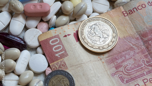 Photo of a 100 Mexican peso bill and two coins among pills of many shapes and colors that could probably be used to illustrate the economics of the pharmaceutical industry  in Mexico.