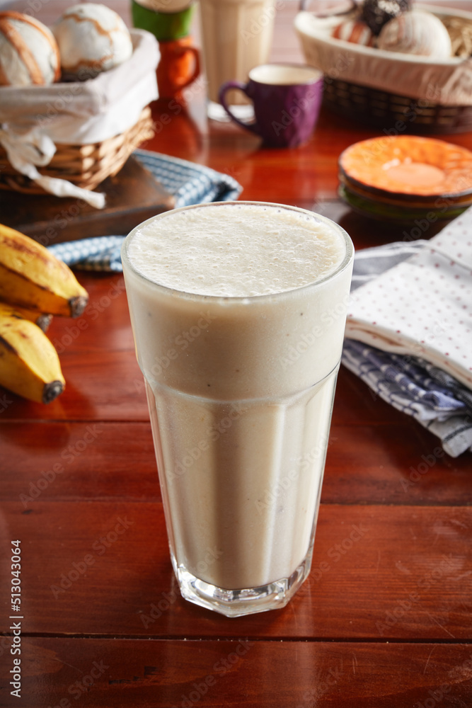 A glass of healthy fresh banana milkshake isolated on wooden background side view A glass of healthy fresh banana milkshake isolated on wooden background side view