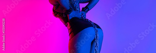sexy buttocks close-up of a girl in a latex bdsm mistress costume with torn tights in neon light photo
