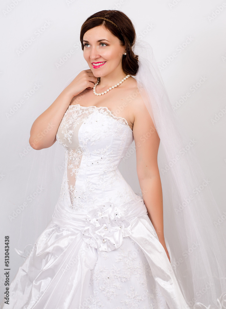 Young girl in a wedding dress with flowers on a light background Young girl in a wedding dress with flowers on a light background