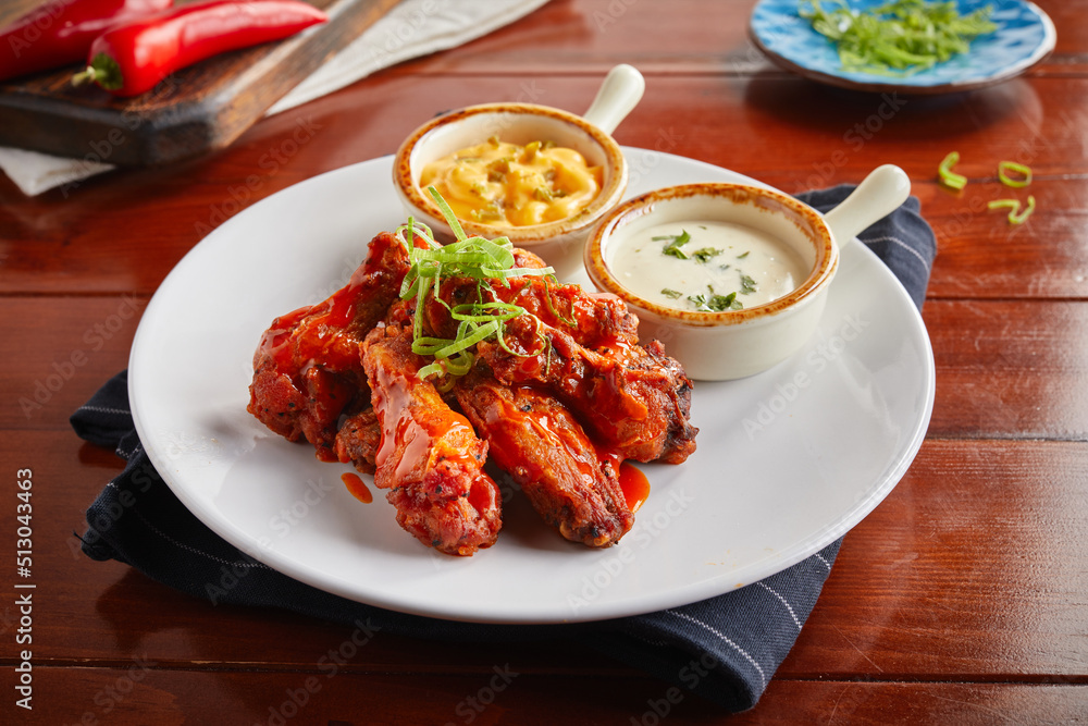 Buffalo chicken wings with cheese and mayo dip served in a dish isolated on wooden background side view