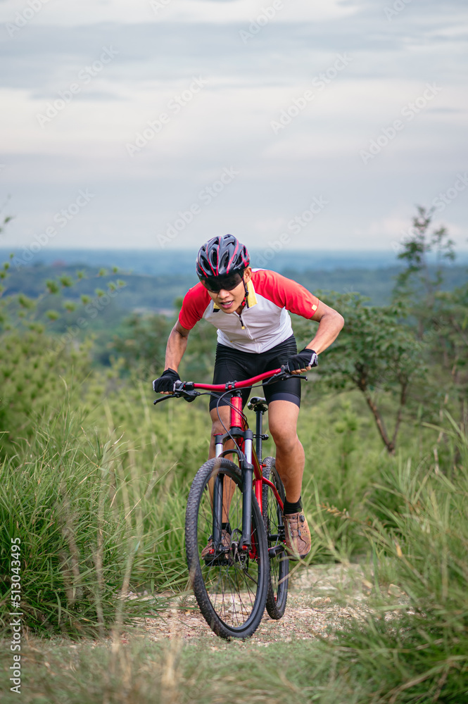 Obraz premium Mountain bikers ride MTB, mountain bike downhill to the extreme. Asian man rides MTB, mountain bike downhill in the wild to extremes. Extreme Sport and MTB, mountain bike downhill Concept.